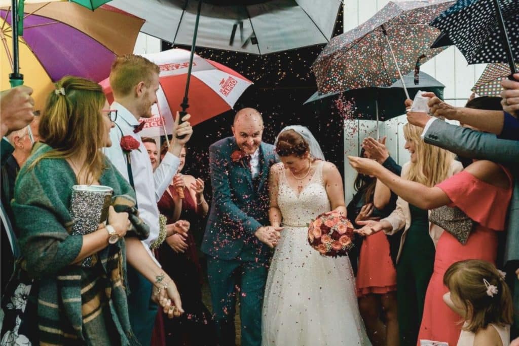 entrée des mariés sous la pluie mariage parapluie invités haie d'honneur sortie mairie cotillon confettis