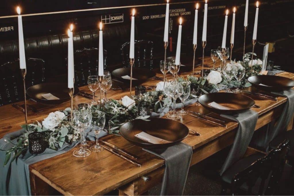 table en bois brut pour salle mariage repas assiettes creuses noires chemin de table vert anglais bougie argenterie
