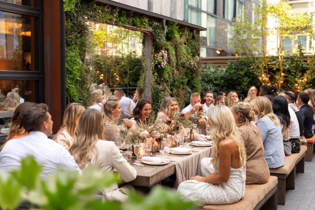 Cérémonie de mariage en petit comité dans un jardin rustique au coucher du soleil avec 20 invités, arche fleurie en pampas et ambiance intime