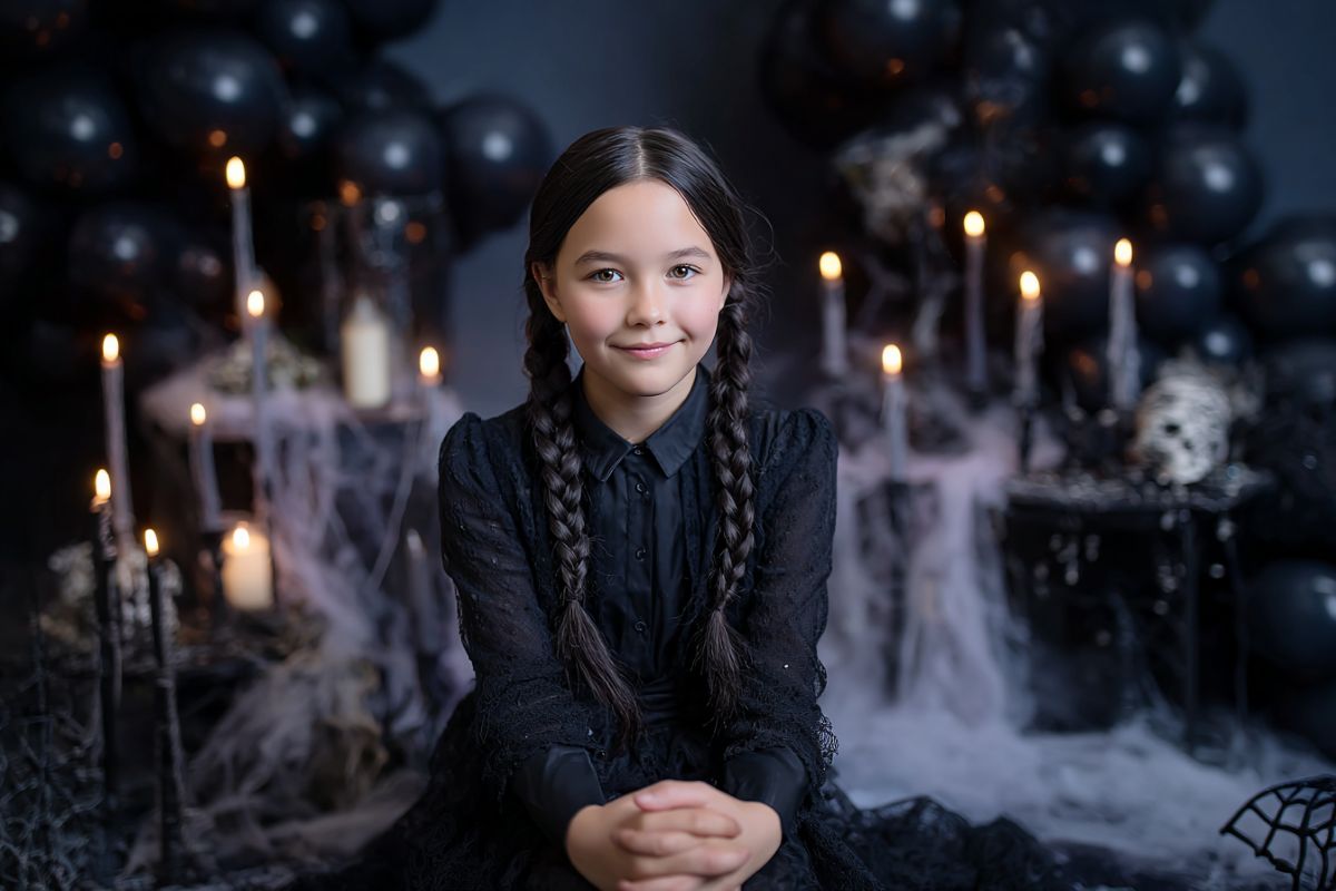 Enfant déguisée en Mercredi Addams lors d’un anniversaire gothique avec ballons noirs et gâteau toile d’araignée