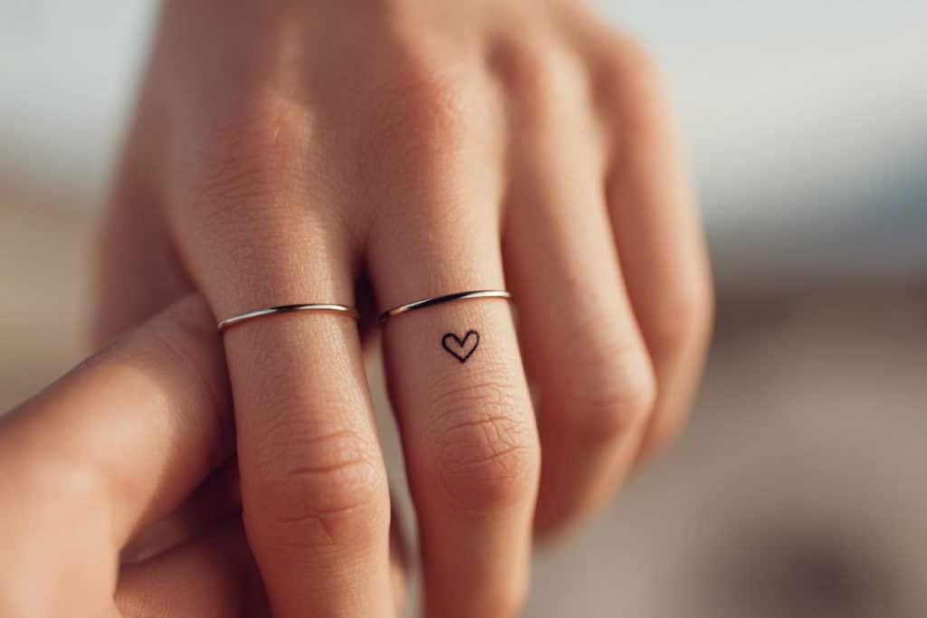 Tatouage alliance minimaliste ligne et cœur discret sur annulaire femme alliance