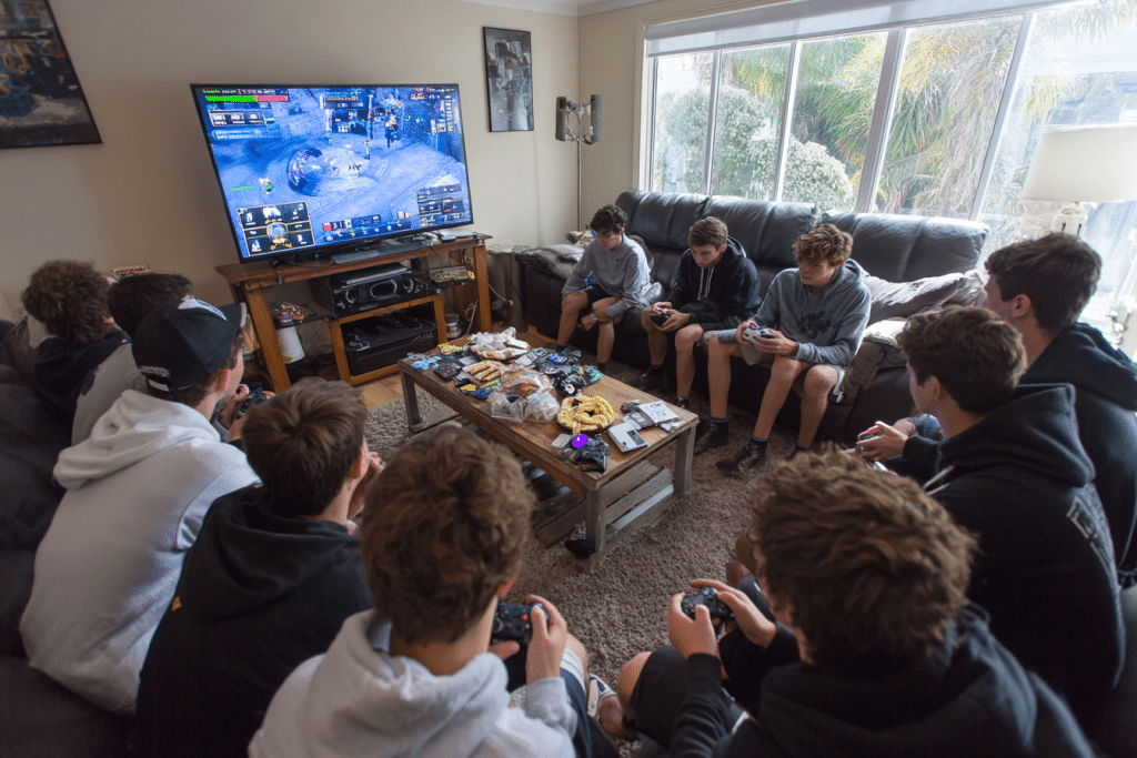 Tournoi gaming 2v2 pour anniversaire 14 ans avec groupe complet de garçons jouant et regardant dans un salon
