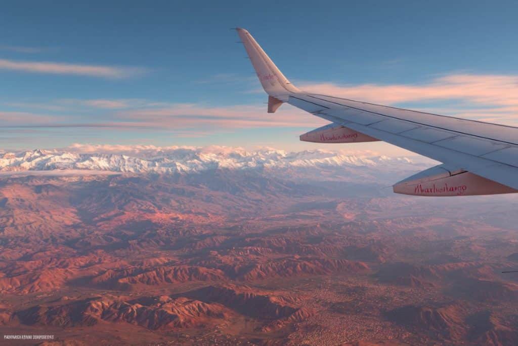 Vol Paris–Marrakech symbolisant le voyage des invités pour un mariage au Maroc montagne atlas fond neige vue ailes avion