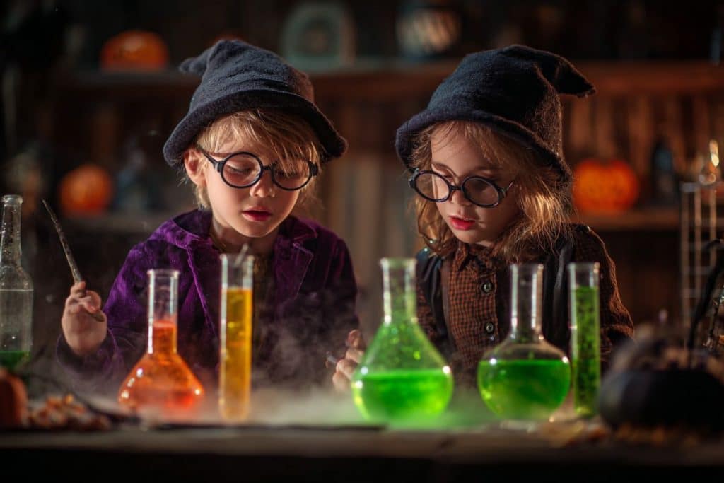 Enfants déguisés créant des potions magiques dans des tubes à essai pendant Halloween
