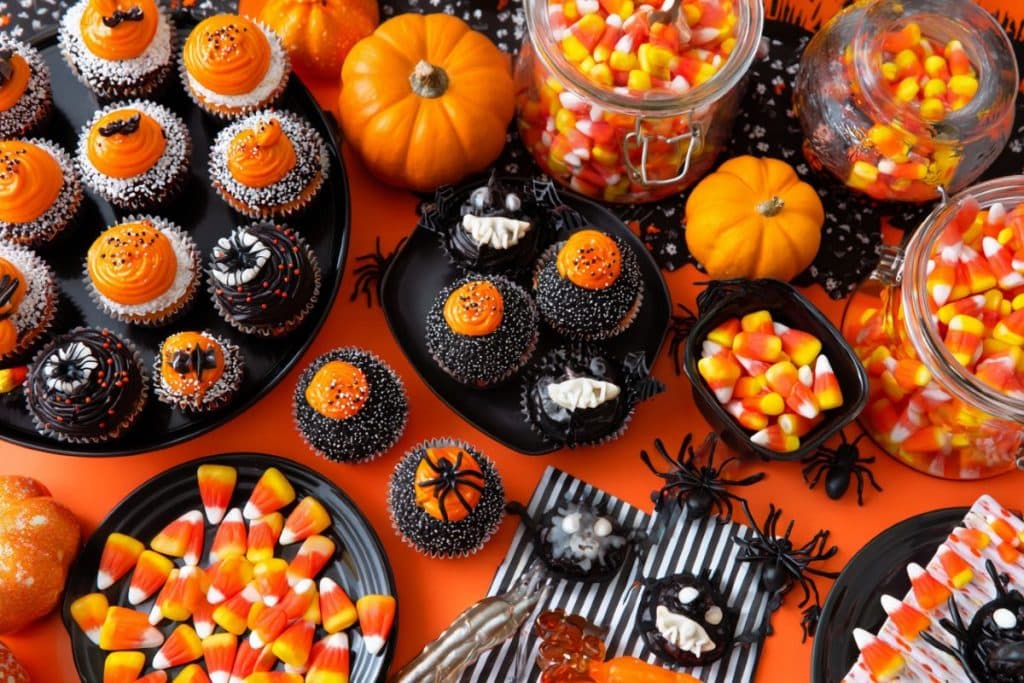 Buffet d’anniversaire Halloween avec cupcakes noirs et orange et bonbons effrayants araignées table