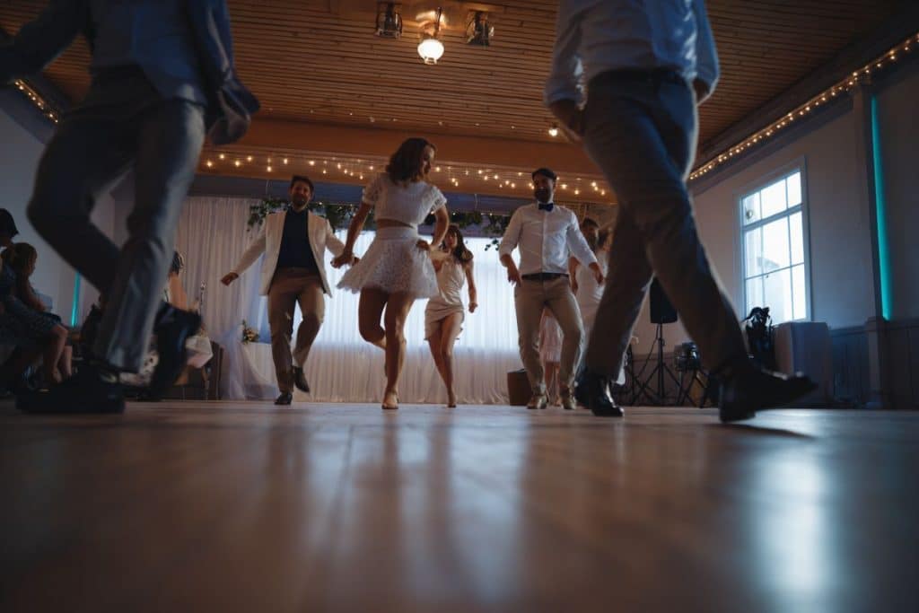 Gros plan sur les pieds des invités exécutant les pas du Madison sur parquet, lumière chaude