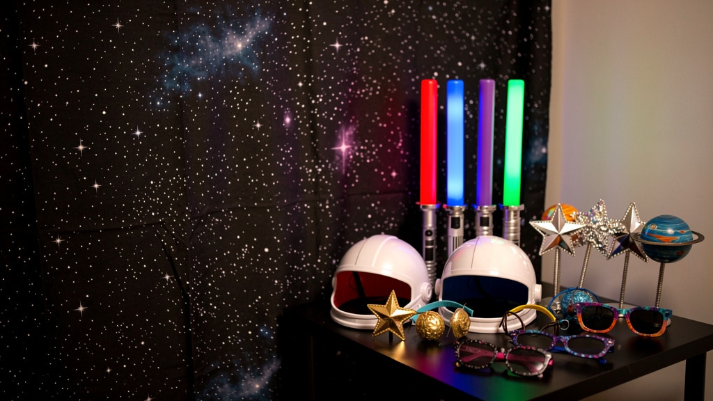 Coin photobooth d'un anniversaire Star Wars avec fond étoilé et accessoires de sabre